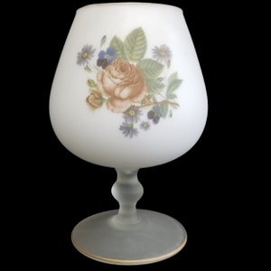 May include: A frosted glass vase with a gold rim and a floral design featuring a rose and other flowers in shades of blue, purple, and yellow.