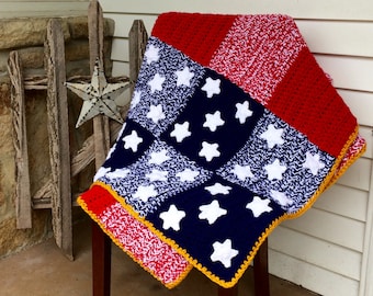 May include: A crocheted blanket with red, white, and blue stripes and white stars. The blanket is folded and draped over a wooden chair.