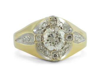 May include: A gold ring with a large round diamond surrounded by smaller diamonds. The ring has a wide band with a textured surface.
