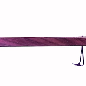 Puede incluir: Un marcapáginas rectangular de madera de color púrpura oscuro con una cuerda púrpura oscura adjunta. El marcapáginas está hecho de una pieza sólida de madera con un acabado liso y pulido. La cuerda está anudada en el extremo.