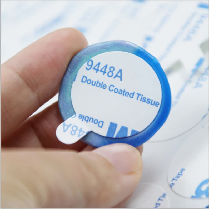 May include: A blue and white round double-sided adhesive sticker with the text "9448A Double Coated Tissue" printed on it.
