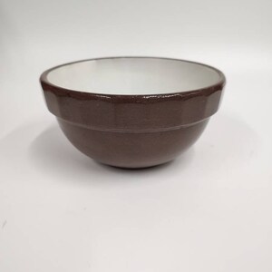 May include: A brown ceramic mixing bowl with a white interior. The bowl has a rounded shape and a slightly flared rim.