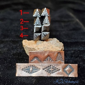 May include: A collection of metal stamps with geometric designs. The stamps include triangular and diamond shapes, with intricate patterns. The stamps are displayed on a dark surface, with a stone and copper plates.