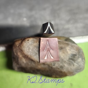 Puede incluir: Un sello de metal con un diseño de árbol y un sello a juego. El sello es de metal y tiene un diseño de árbol. El texto "K2 Stamps" está escrito en cursiva azul en la parte inferior de la imagen.