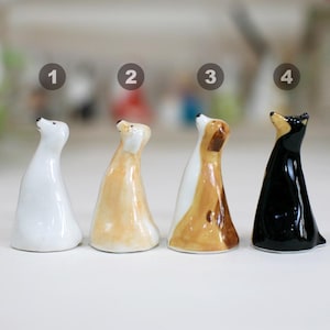 May include: Four ceramic animal figurines, each standing upright with their heads tilted upwards. The figurines are painted in white, light brown, brown and black.