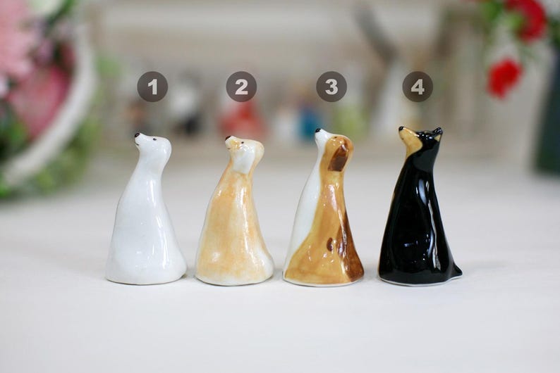 May include: Four ceramic animal figurines, each standing upright with their heads tilted upwards. The figurines are painted in white, light brown, brown and black.