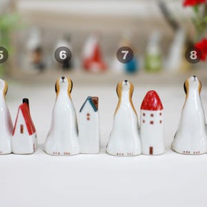 May include: Set of eight ceramic figurines of dogs with houses. The dogs are white with brown spots and are looking up. The houses are various colors and styles.