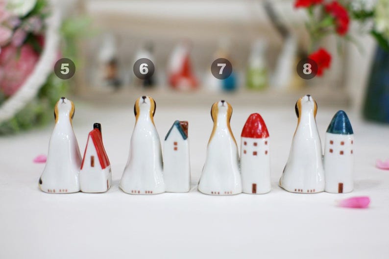 May include: Set of eight ceramic figurines of dogs with houses. The dogs are white with brown spots and are looking up. The houses are various colors and styles.