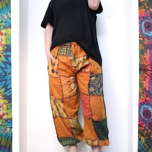 May include: Patchwork trousers with a mix of orange, brown, green and blue fabrics. The trousers have a drawstring waist and a relaxed fit.
