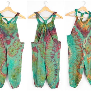 May include: Tie-dye jumpsuit in a green, blue and red colour scheme. The jumpsuit has a halter top with a knotted detail at the back.