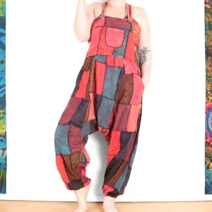 May include: A patchwork jumpsuit featuring a mix of colours and patterns, including red, blue, brown and black. The jumpsuit has a wide leg and a relaxed fit.