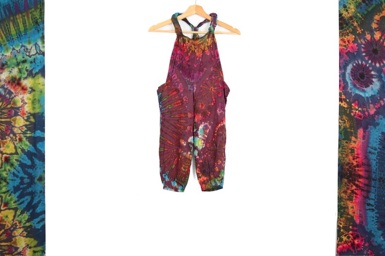 May include: Tie-dye print jumpsuit with a halter neck and a loose fit. The jumpsuit is made of a soft, comfortable fabric and has a vibrant color scheme.