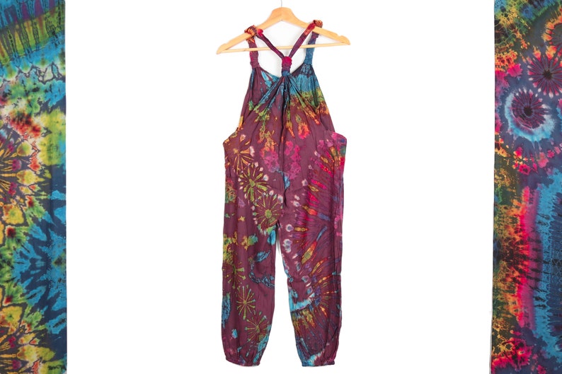 May include: A tie-dye jumpsuit with a halter top and a loose fit. The jumpsuit is made of a soft, comfortable fabric and features a vibrant color scheme with shades of purple, blue, green, and yellow.
