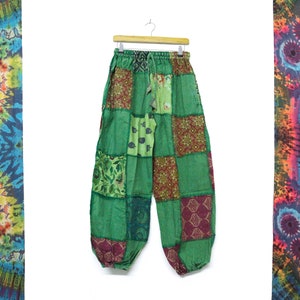 Op de afbeelding: Groene patchwork broek met verschillende kleurrijke patronen. De broek heeft een trekkoord in de taille en een losse, comfortabele pasvorm.