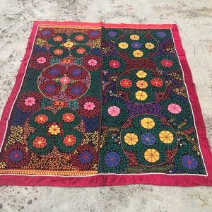 May include: A large, rectangular, hand-stitched rug with a black background and colorful floral patterns. The rug is made of a dark fabric with a red border.