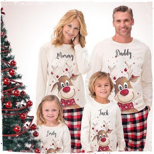 Può includere: Maglie a maniche lunghe color crema abbinate con grafiche di renne e pantaloni a quadri rossi e neri. Le maglie riportano i nomi Mommy, Daddy, Jack ed Emily sopra le renne. Le renne indossano sciarpe rosse con fiocchi di neve bianchi.