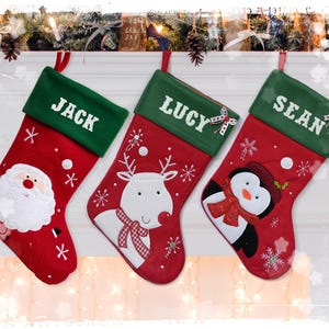 Può includere: Tre calze di Natale rosse e verdi con nomi personalizzati: Jack, Lucy e Sean. Ogni calza presenta un diverso design ricamato: Babbo Natale, una renna e un pinguino.