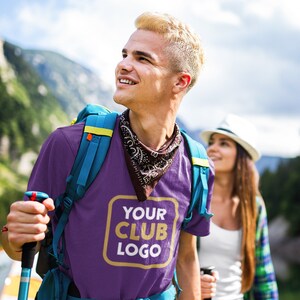 Op de afbeelding: Een man draagt een paars T-shirt met een blauwe rugzak en een bandana om zijn nek. Het T-shirt heeft een gouden rechthoek met de tekst "YOUR CLUB LOGO".