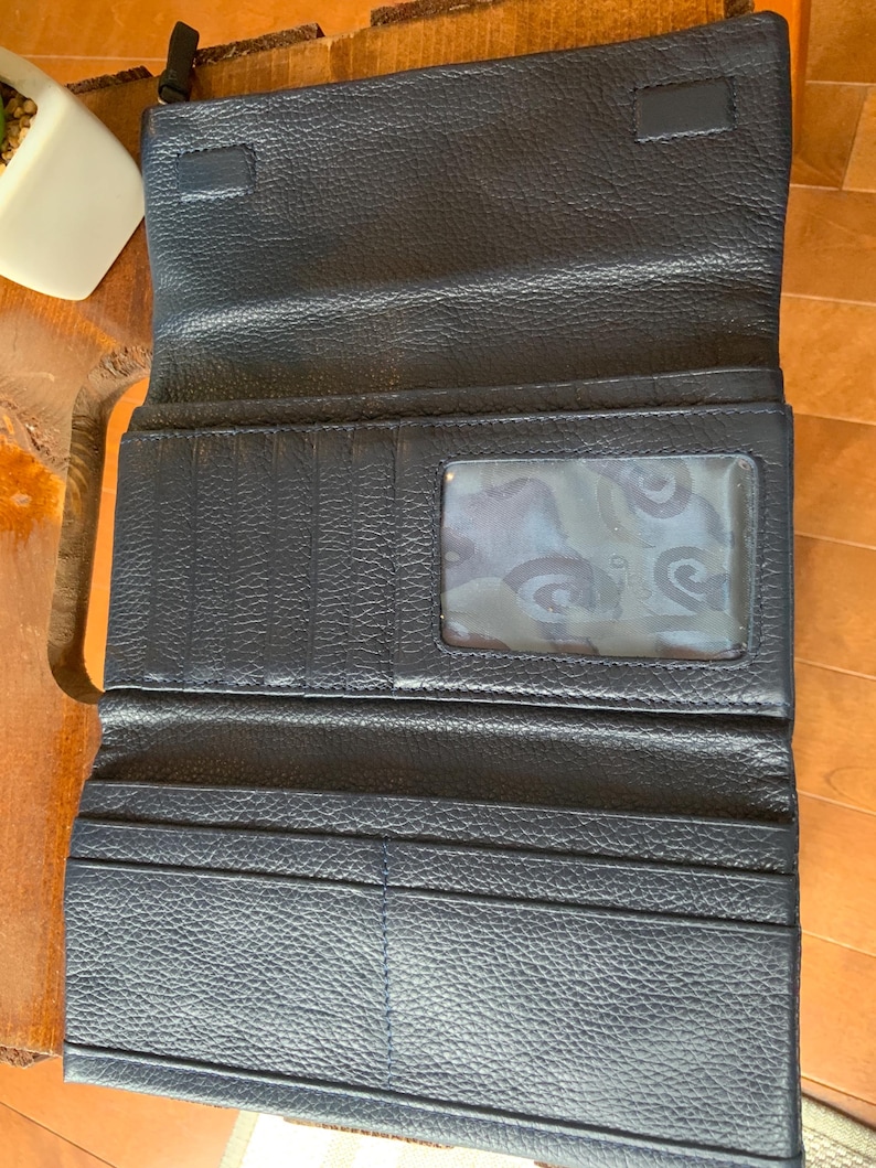 May include: Open navy blue leather wallet with multiple card slots and a clear ID window. The wallet is unfolded, revealing its interior compartments. The leather has a textured grain, and the wallet appears to be new.