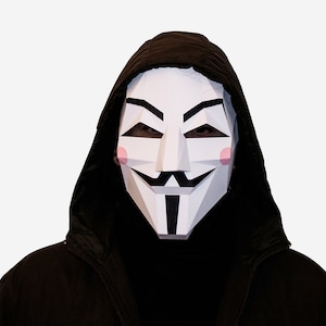 Puede incluir: Una persona con una sudadera con capucha negra y una máscara de papel blanca con un diseño estilizado. La máscara tiene un bigote negro y una sonrisa negra.