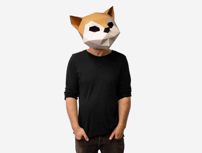 May include: A person wearing a brown and white origami-style fox mask. The mask has a geometric design and covers the person's entire head.