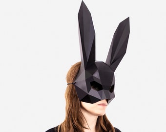 Puede incluir: Una máscara de conejo de origami negra con formas geométricas. La máscara cubre los ojos y la nariz y tiene una nariz larga y puntiaguda.