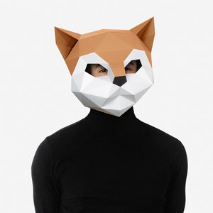 May include: A person wearing a brown and white origami fox mask with black eyes. The mask is made of paper and has a geometric design. The person is wearing a black turtleneck sweater.