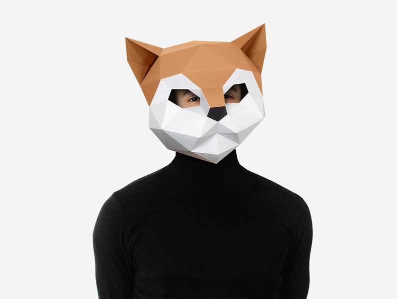 May include: A person wearing a brown and white origami fox mask with black eyes. The mask is made of paper and has a geometric design. The person is wearing a black turtleneck sweater.