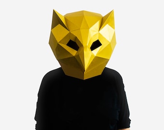 May include: A person wearing a yellow origami owl mask. The mask is made of paper and has a geometric design. The person is wearing a black shirt.
