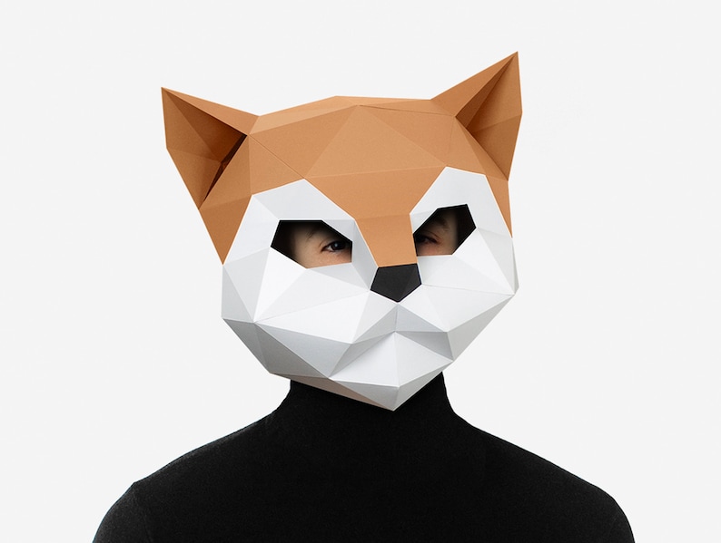 May include: A person wearing a brown and white origami fox mask. The mask is made of paper and has a geometric design.
