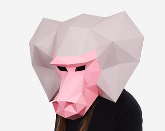 May include: A pink and gray papercraft mask of a baboon's head. The mask is made of folded paper and has a realistic appearance.