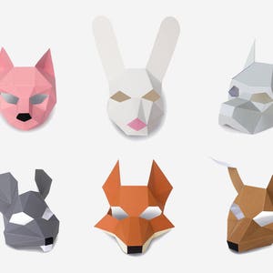 Peut inclure: Six masques d'animaux géométriques en papier : un chat rose, un lapin blanc, un chien gris, une souris grise, un renard orange et un cerf marron. Chaque masque a des découpes pour les yeux.