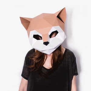 May include: A person wearing a brown and white papercraft fox mask. The mask is made of folded paper and has a realistic design. The person is wearing a black shirt.