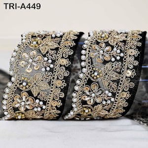 May include: A black mesh ribbon trim labeled TRI-A449, featuring intricate gold metallic embroidery, small white beads, and circular gold sequins arranged in a floral pattern along the edges and center of the decorative fabric border.