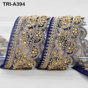 May include: A navy blue lace trim featuring gold metallic embroidery in a floral pattern with small white beads and gold tube beads. The trim has a scalloped edge and the text TRI-A394 is visible in the upper left corner of the image.