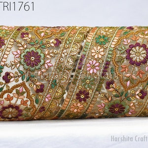 May include: Close-up of an embroidered trim with floral and geometric patterns. The trim has a beige mesh base with gold, green, pink, and purple embroidery. The trim is embellished with sequins and has the text "GTR1761".