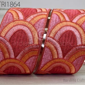 a decorative red and orange embroidered ribbon with a repeating pattern of arches and circles.