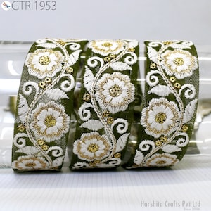 Pode incluir: Close-up de três fitas bordadas verde-oliva com desenhos florais brancos e detalhes dourados. As fitas são intrincadamente detalhadas com fio branco e lantejoulas douradas, mostrando um delicado padrão floral. O texto "GTR1953" está no canto superior esquerdo.