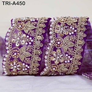 May include: A purple mesh ribbon trim labeled TRI-A450, featuring intricate gold metallic embroidery, floral patterns, small white faux pearls, and circular gold sequins arranged in a repeating decorative border design.