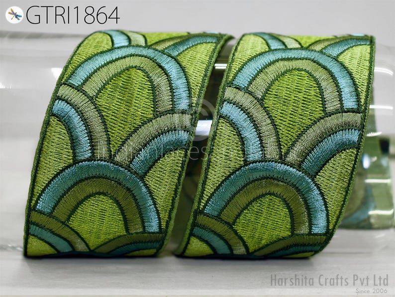 two pieces of embroidered fabric with a repeating pattern of green and blue waves or circles. The fabric appears to be a decorative textile, possibly used for clothing or home decor.