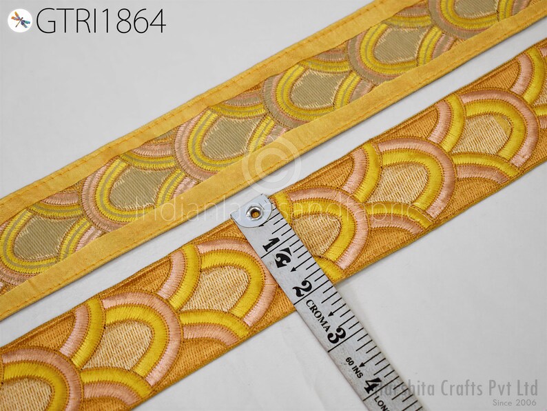 a close-up view of a decorative fabric with a repeating pattern of yellow and orange circles, and a ruler is placed next to it to measure the length of the fabric.