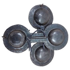 May include: A set of four castanets, a traditional Spanish percussion instrument, made of wood and metal. The castanets are connected by a leather strap and have a dark grey finish.