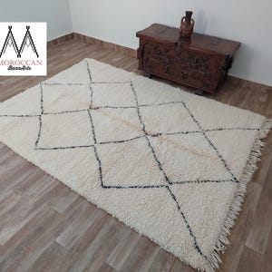 Authentic Beni Ourain Moroccan rug in cream handwoven wool with black diamond lattice, fringed edges on a 5x9 area rug.