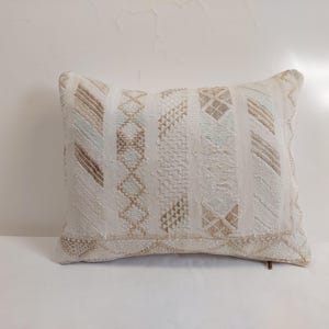 Peut inclure: Coussin rectangulaire décoratif crème avec un motif géométrique beige et bleu clair. Le coussin a une surface texturée et est adapté à la décoration intérieure. Dimensions en centimètres.