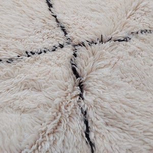 Authentic Beni Ourain Moroccan rug in cream handwoven wool with black diamond lattice, fringed edges on a 5x9 area rug.