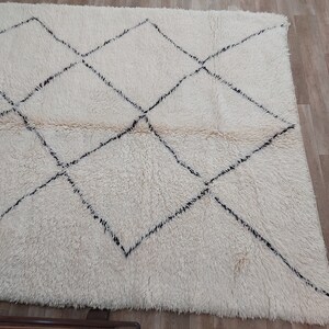 Authentic Beni Ourain Moroccan rug in cream handwoven wool with black diamond lattice, fringed edges on a 5x9 area rug.