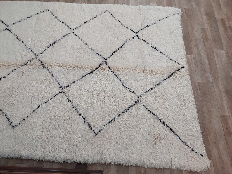 Authentic Beni Ourain Moroccan rug in cream handwoven wool with black diamond lattice, fringed edges on a 5x9 area rug.