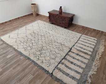May include: A white and black Moroccan rug with a geometric pattern. The rug has a fringe border and is made of wool.