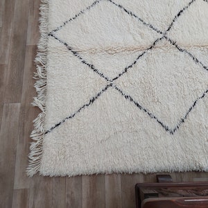 Authentic Beni Ourain Moroccan rug in cream handwoven wool with black diamond lattice, fringed edges on a 5x9 area rug.