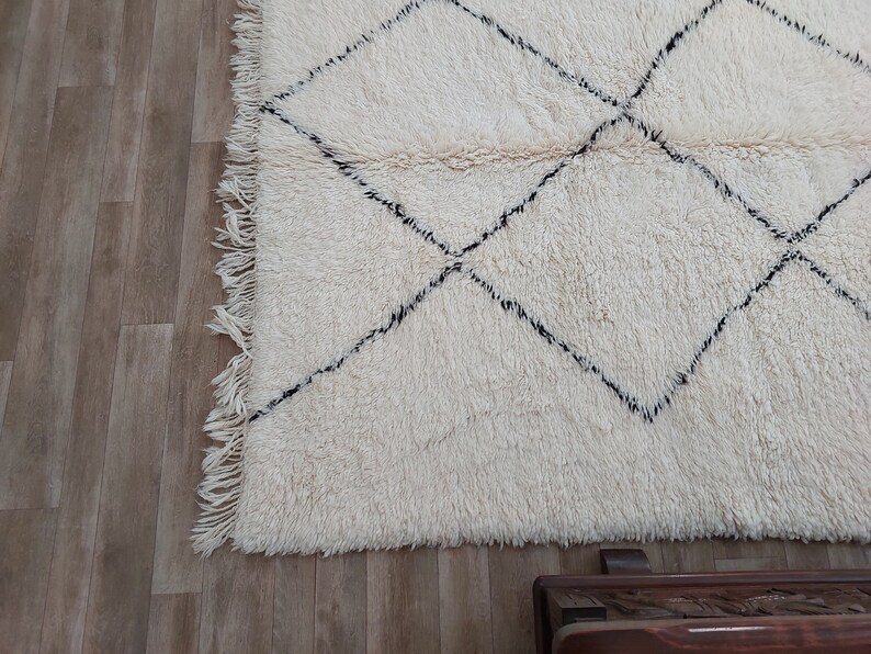 Authentic Beni Ourain Moroccan rug in cream handwoven wool with black diamond lattice, fringed edges on a 5x9 area rug.